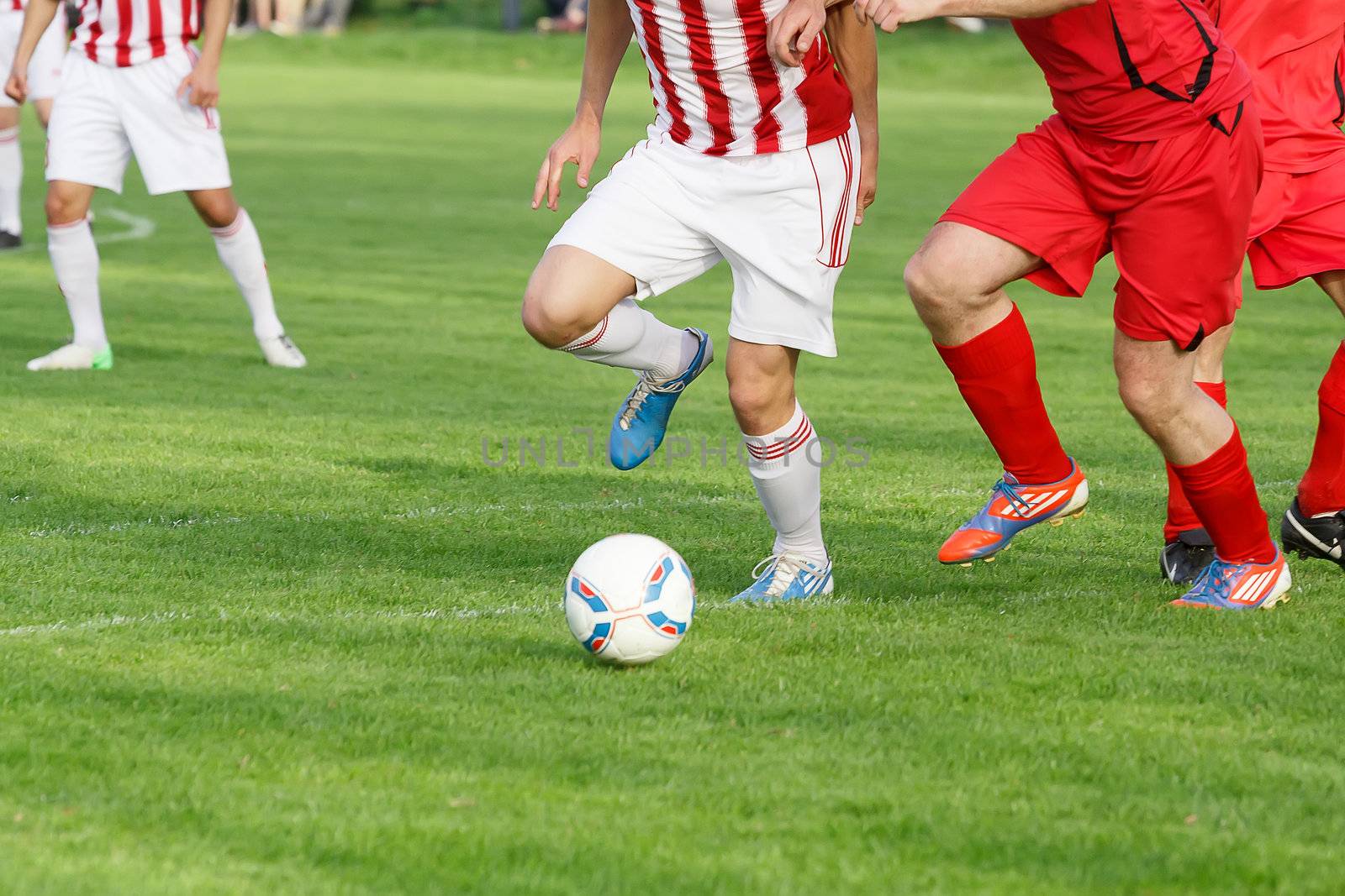 Soccer player legs dribbling in a match on green grass