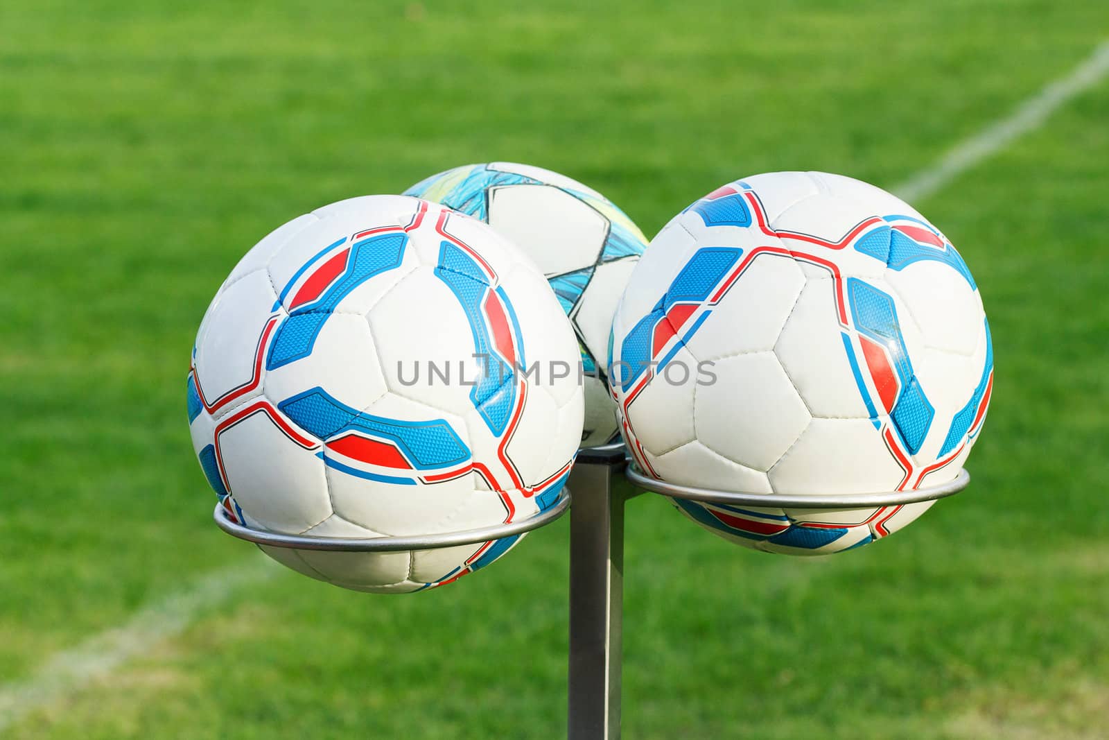 three football bals on holders with green grass in background