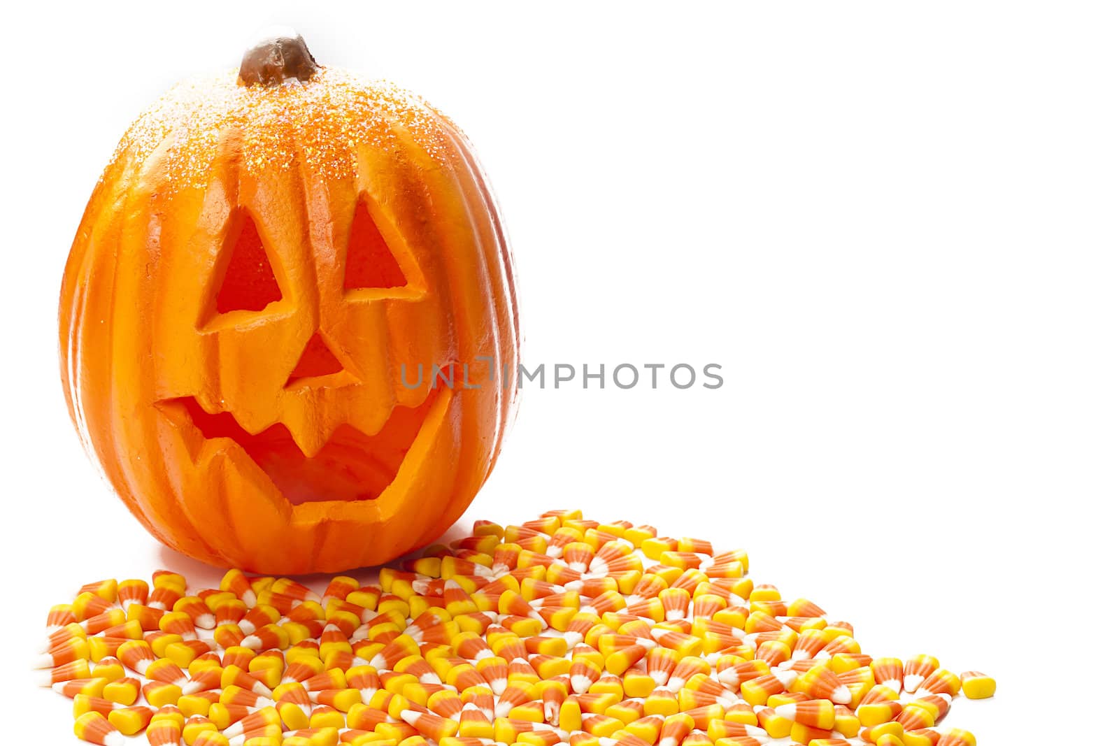 Jack o lantern with candy corn infornt of it.