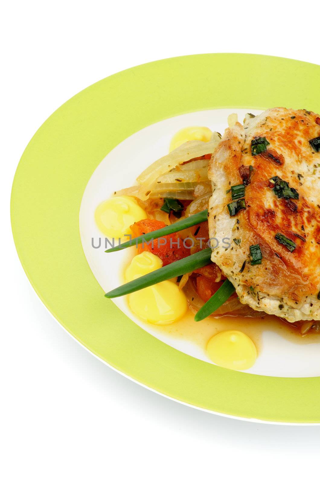 Delicious Pork Chop on Vegetable Saute Garnish with Spring Onion and Cheese Sauce on Green Plate closeup on white background
