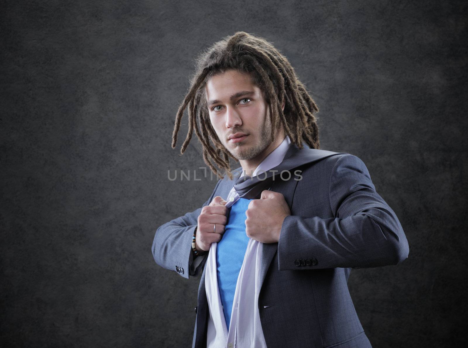 Young man dressed in suit, shirt and tie pulling open shirt 