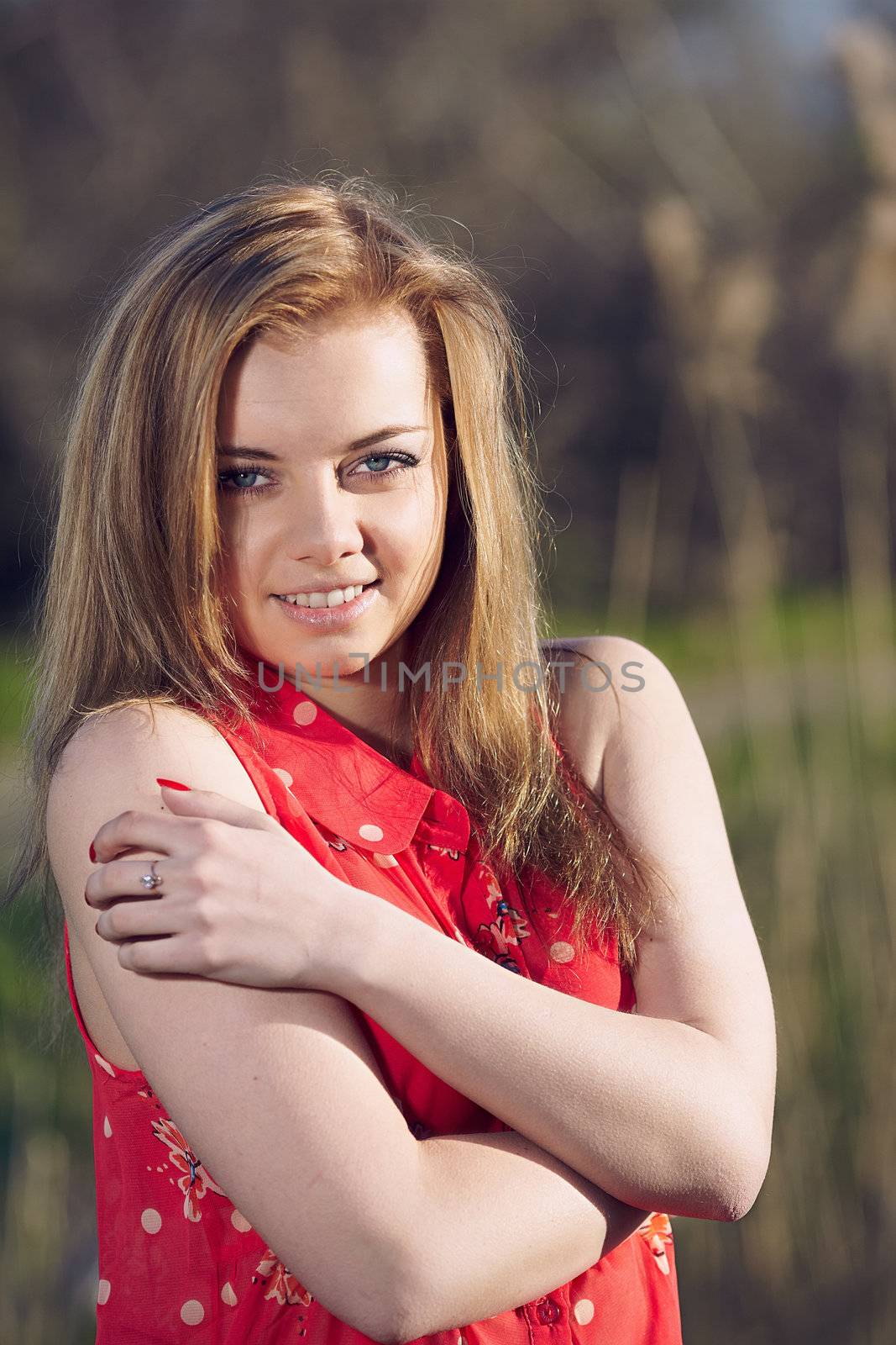 Beautiful woman in a red dress on a background of reeds