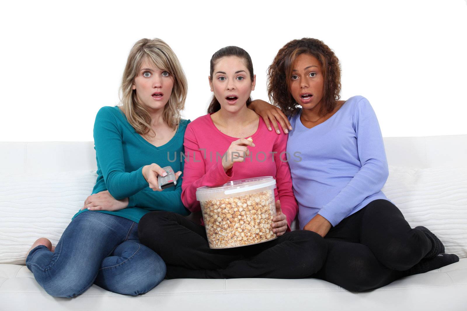 three friends watching television and eating popcorn by phovoir