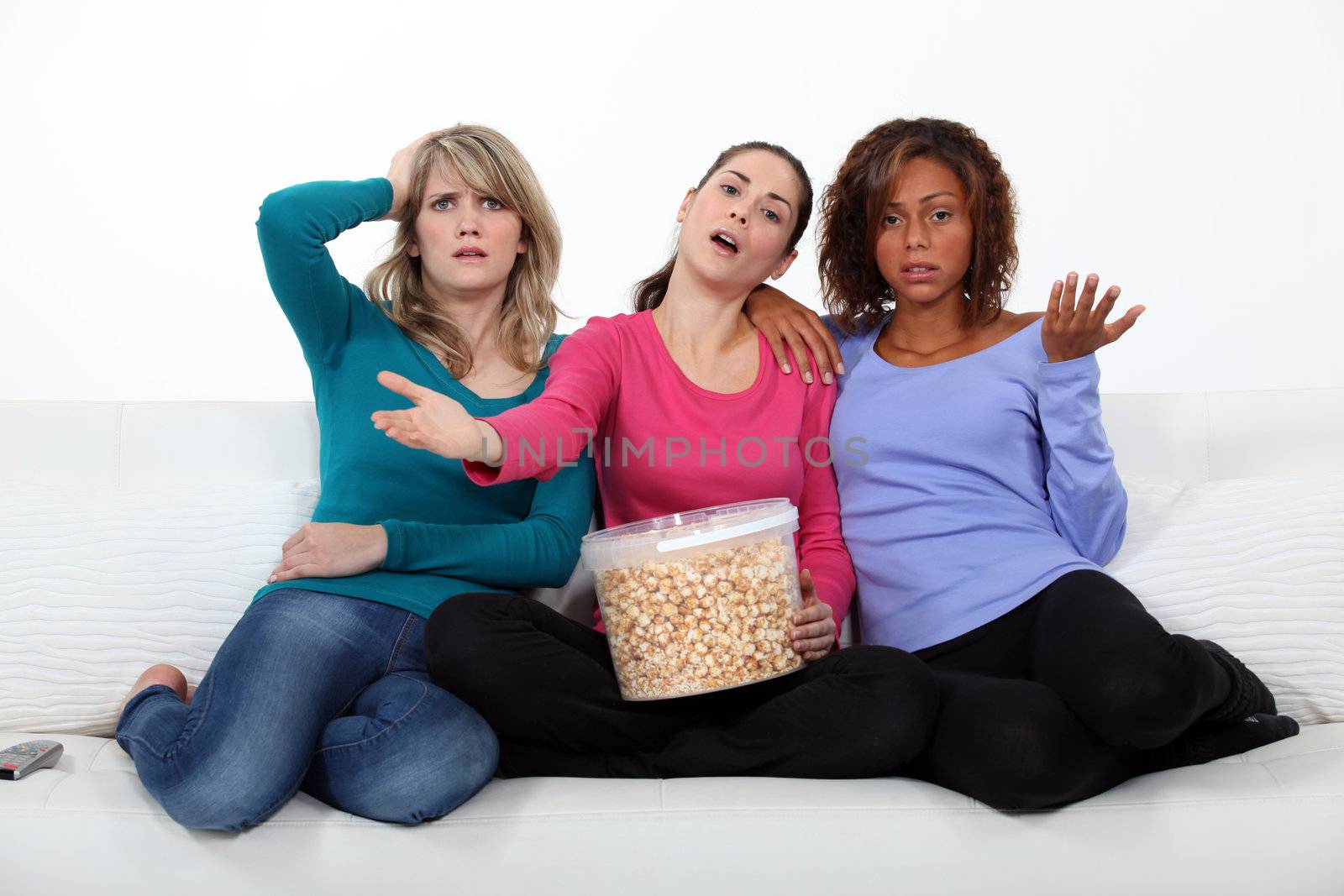 friends watching television and eating popcorn by phovoir