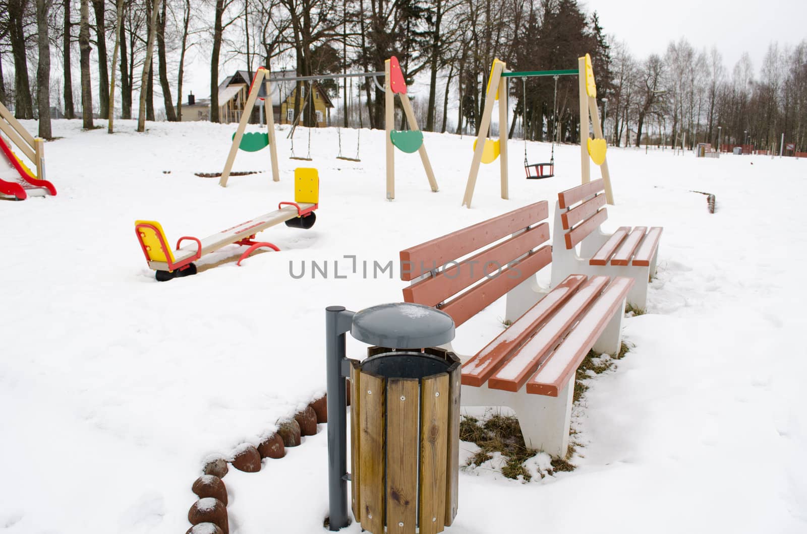 recreational leisure zone in park. playground benches and swings between snow in winter.