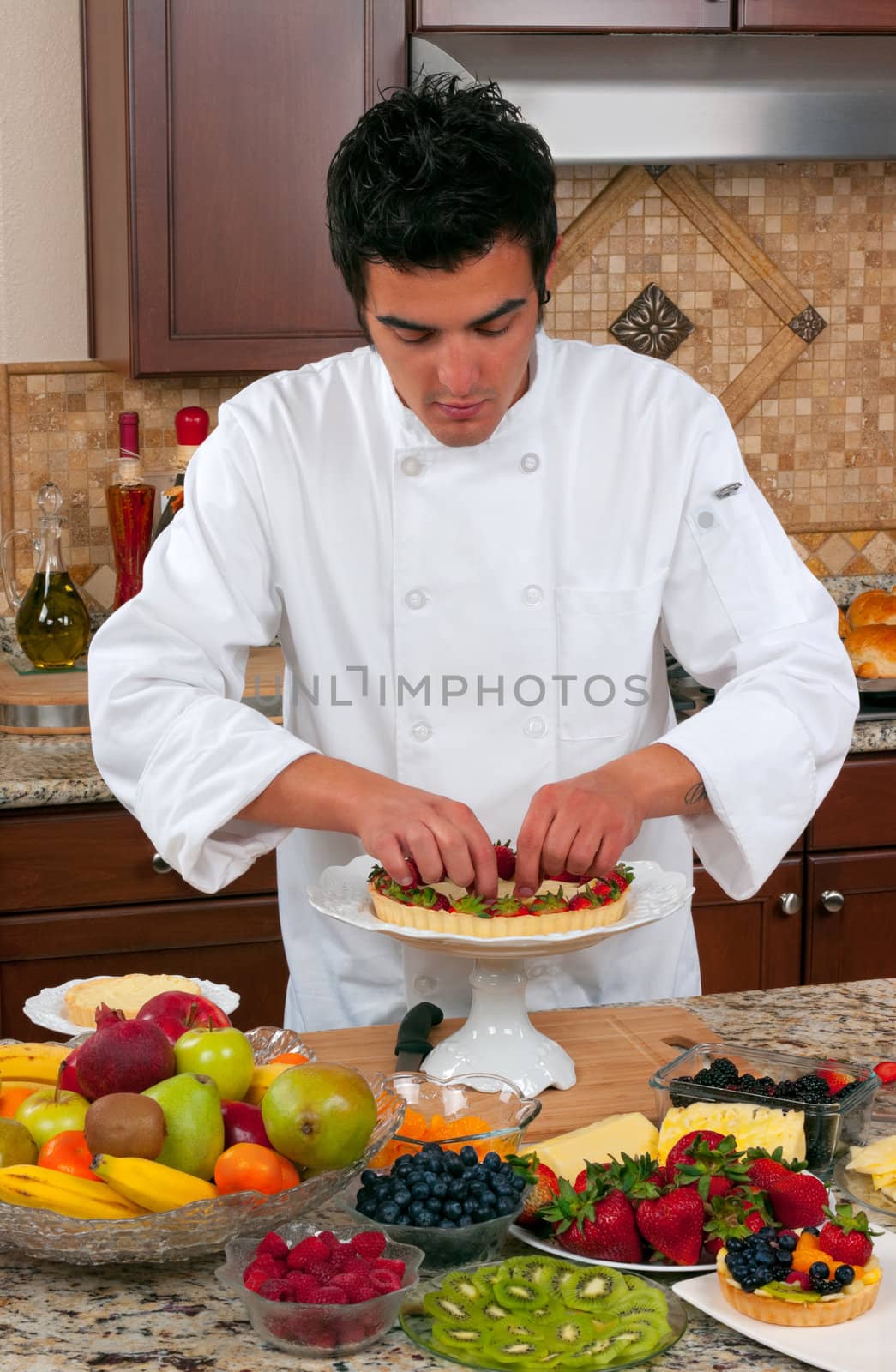 Young handsome chef making fruit tarts