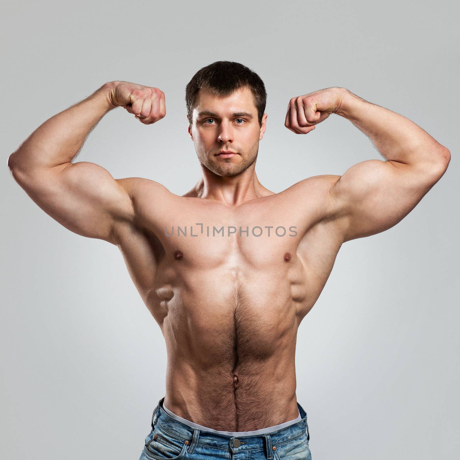 Handsome muscular guy with naked torso isolater over a grey background