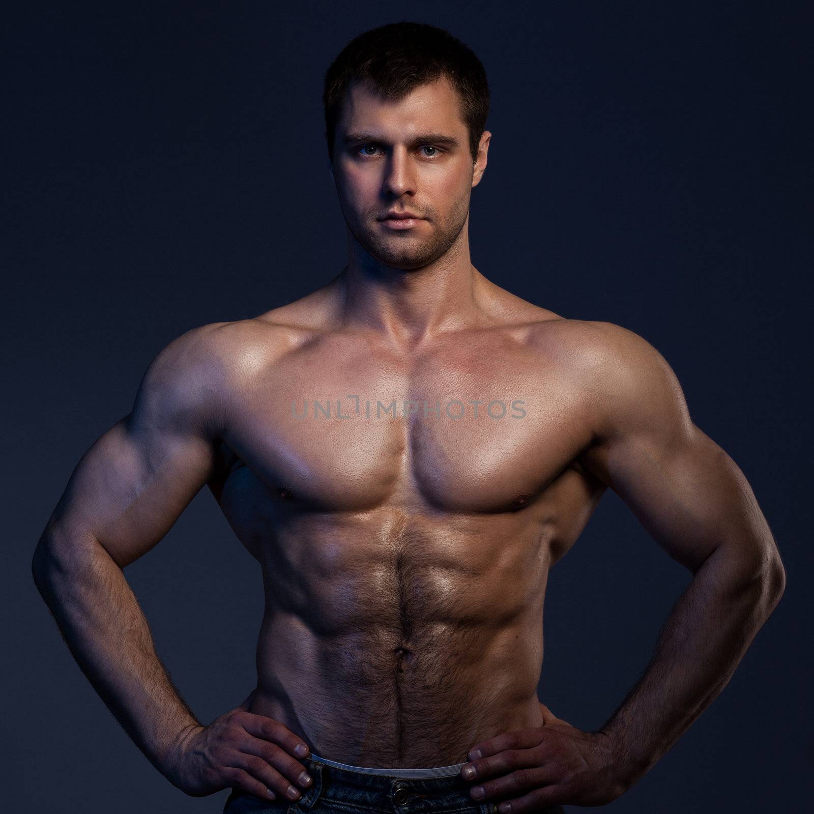 Closeup portrait of handsome muscular guy on dark background