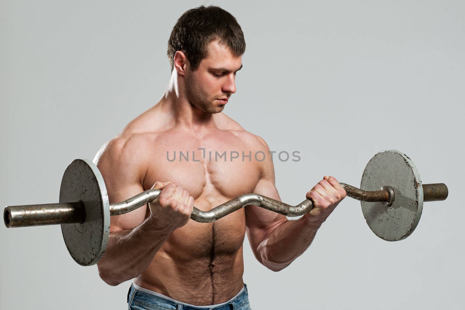 Handsome guy working out with dumbbells isolated over grey background