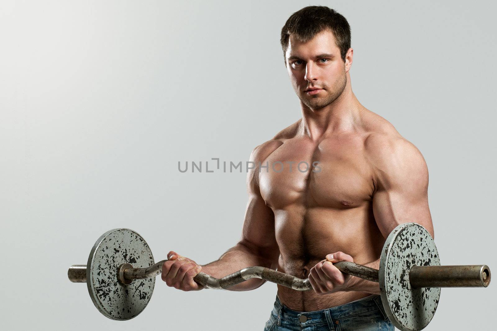 Handsome guy working out with dumbbells isolated over grey background