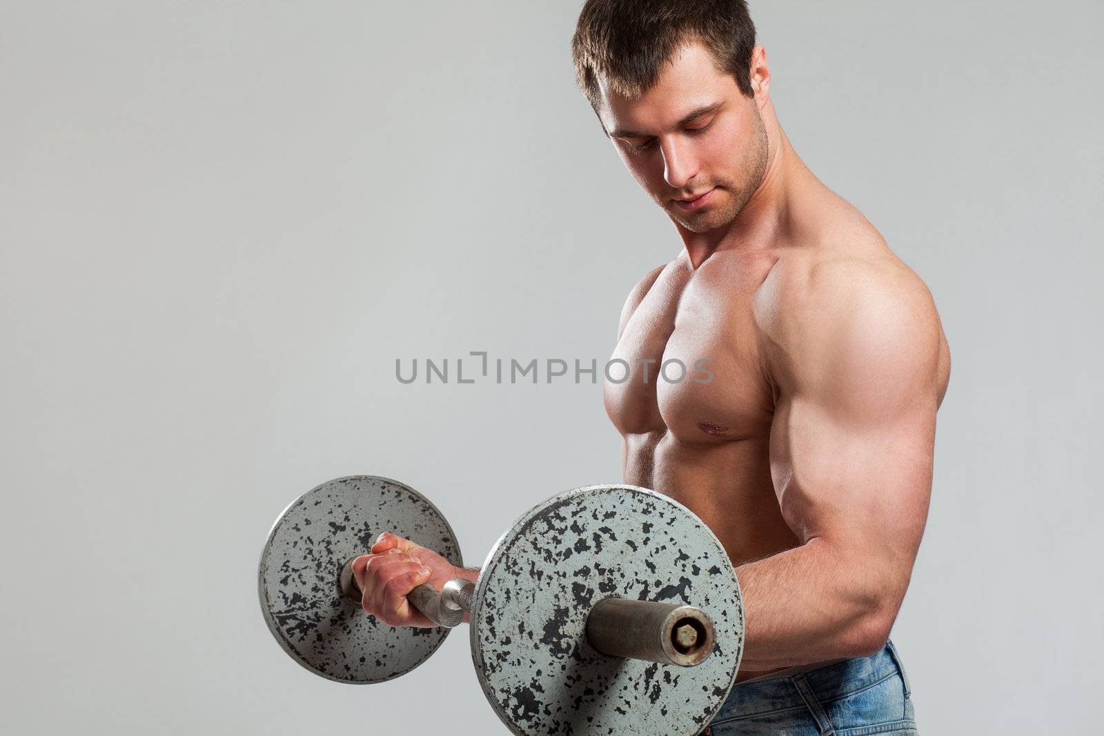 Handsome guy working out with dumbbells isolated over grey background