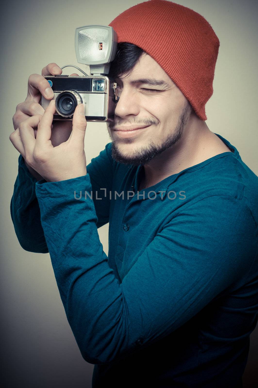 young stylish man holding old camera on vignetting background
