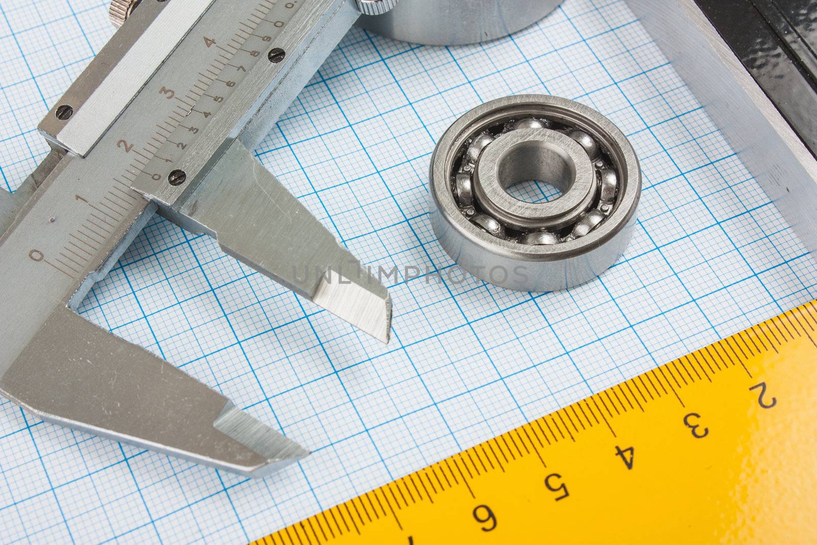 calipers, bearing and square on the background of graph paper