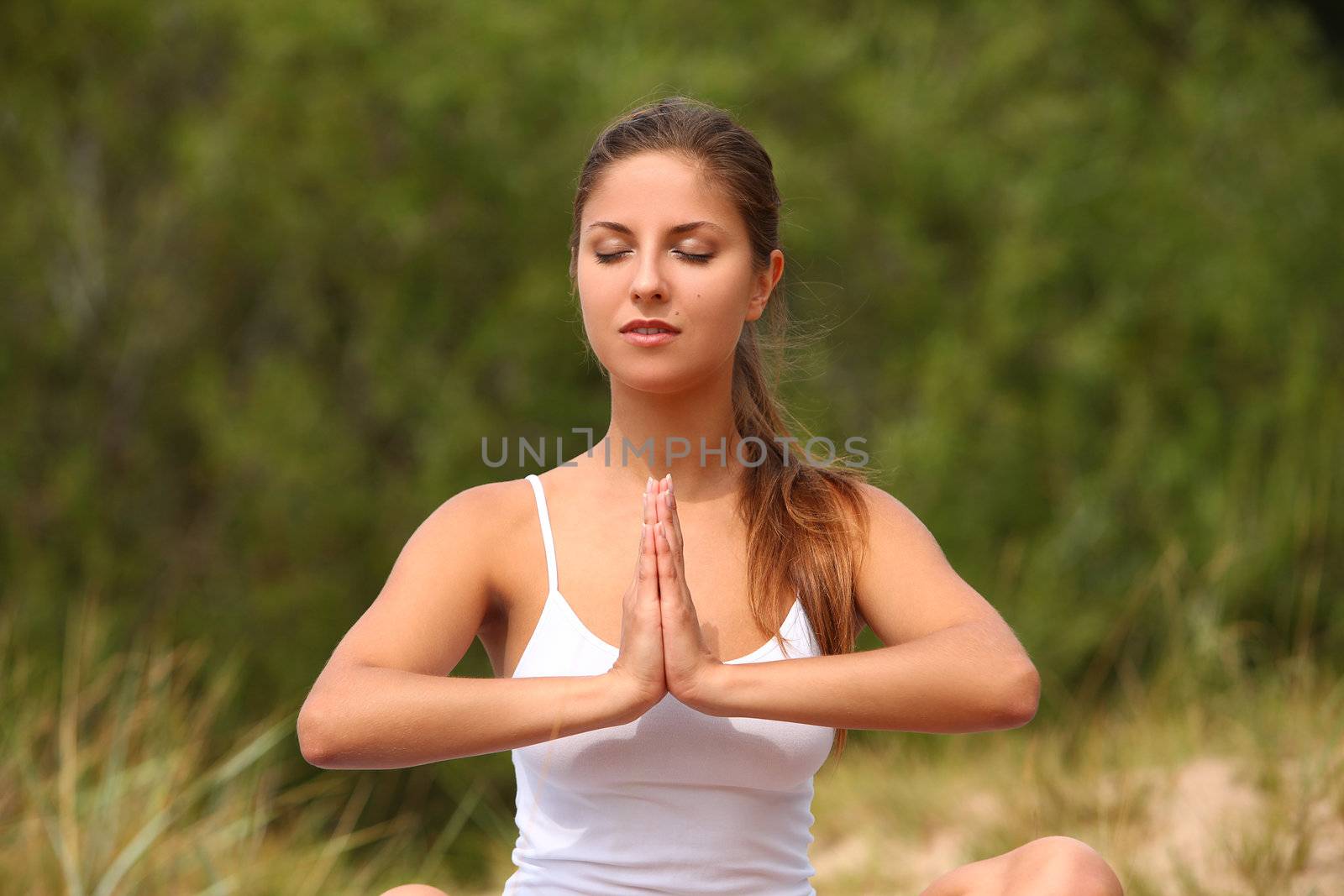 Beautiful caucasian woman enjoys yoga in a green forest