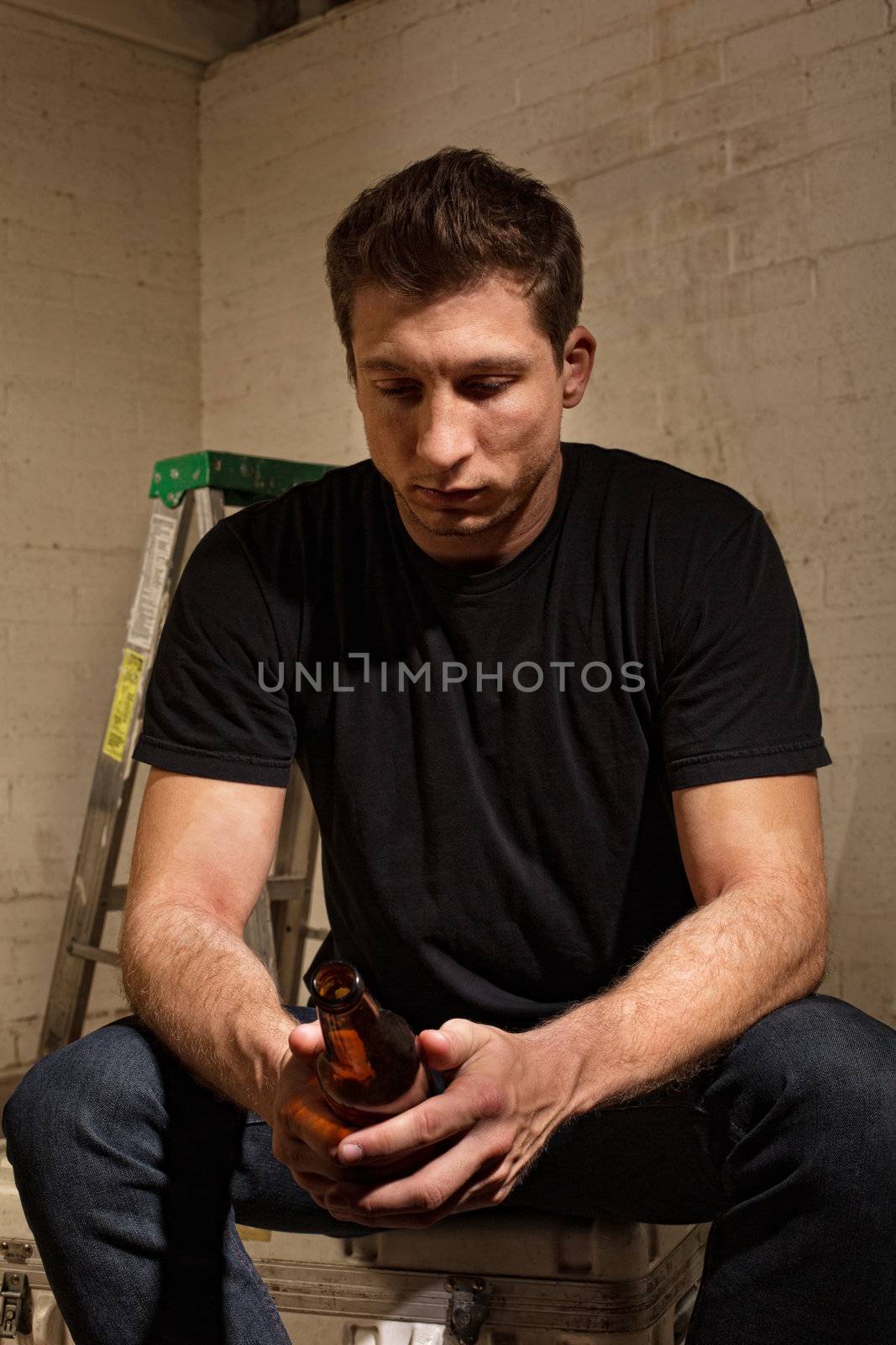 Depressed Caucasian man looking at a glass bottle