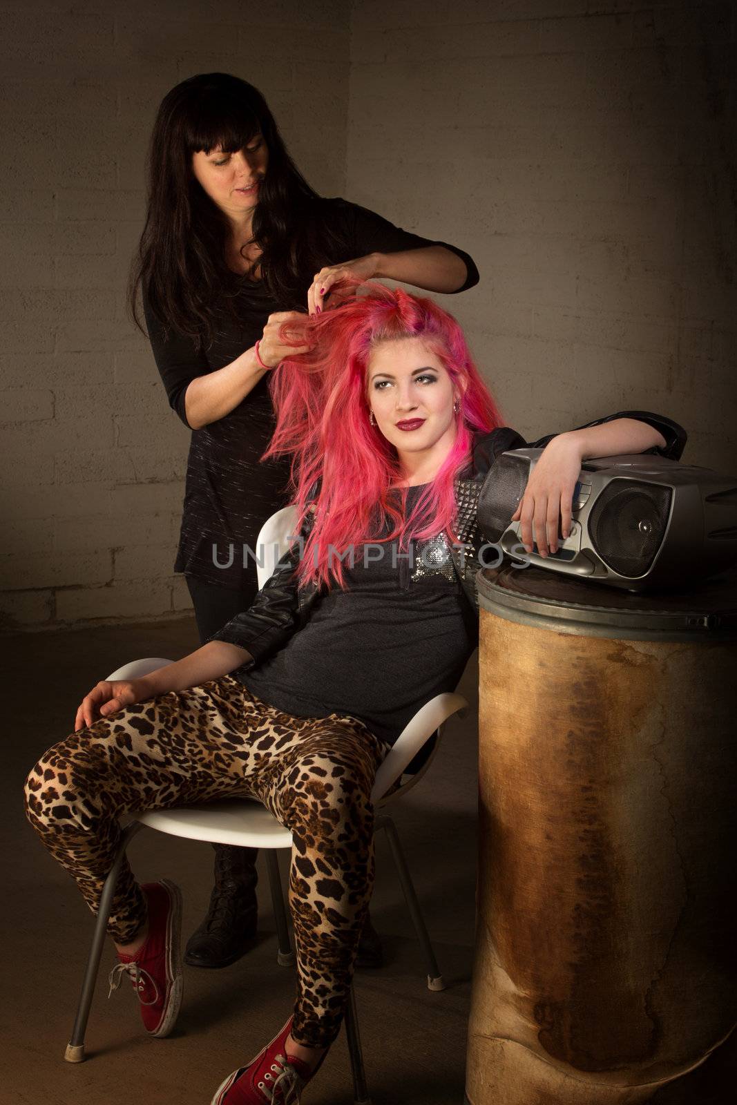 Young punk rocker leaning back with hair stylist working