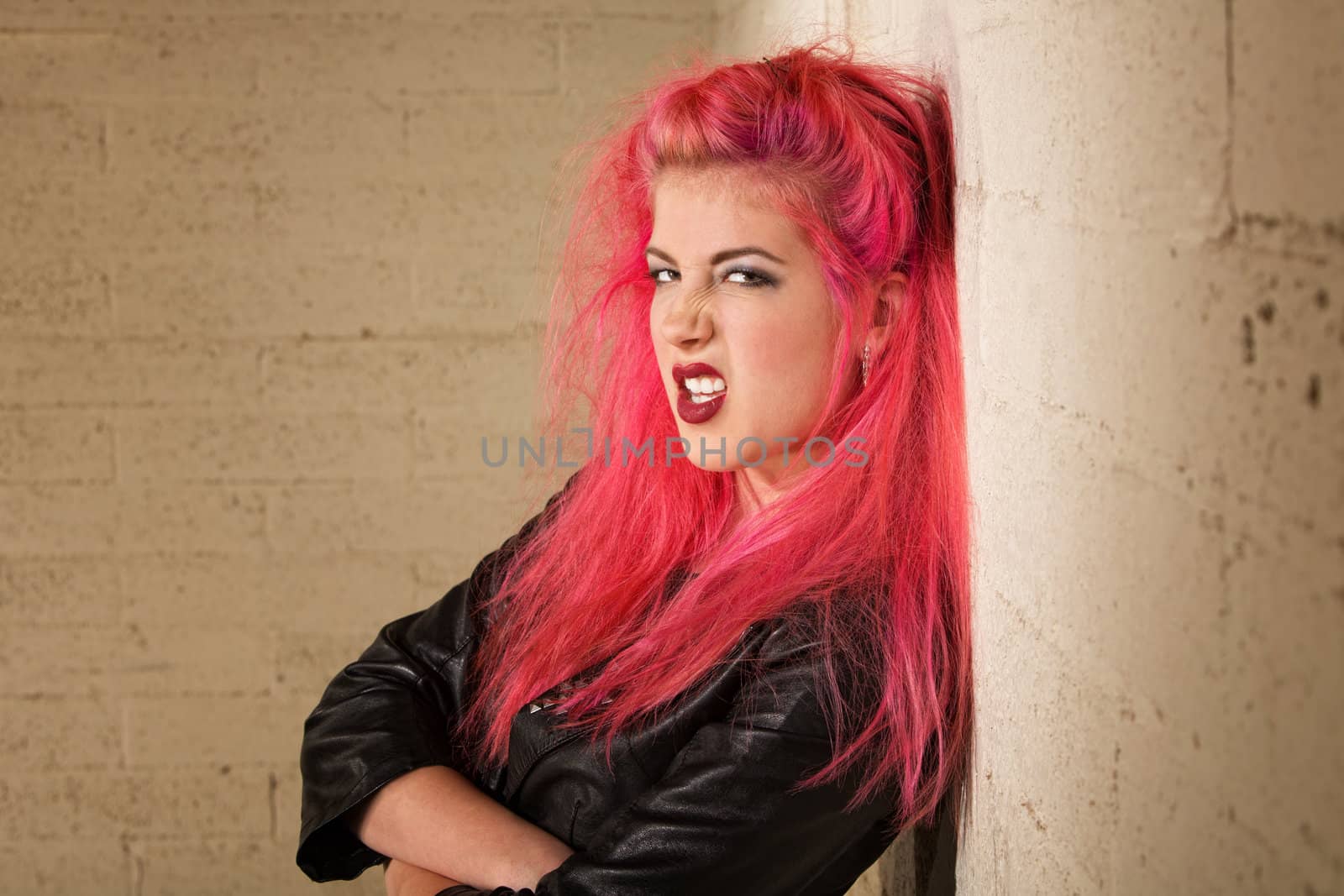 Sneering young female with folded arms against the wall