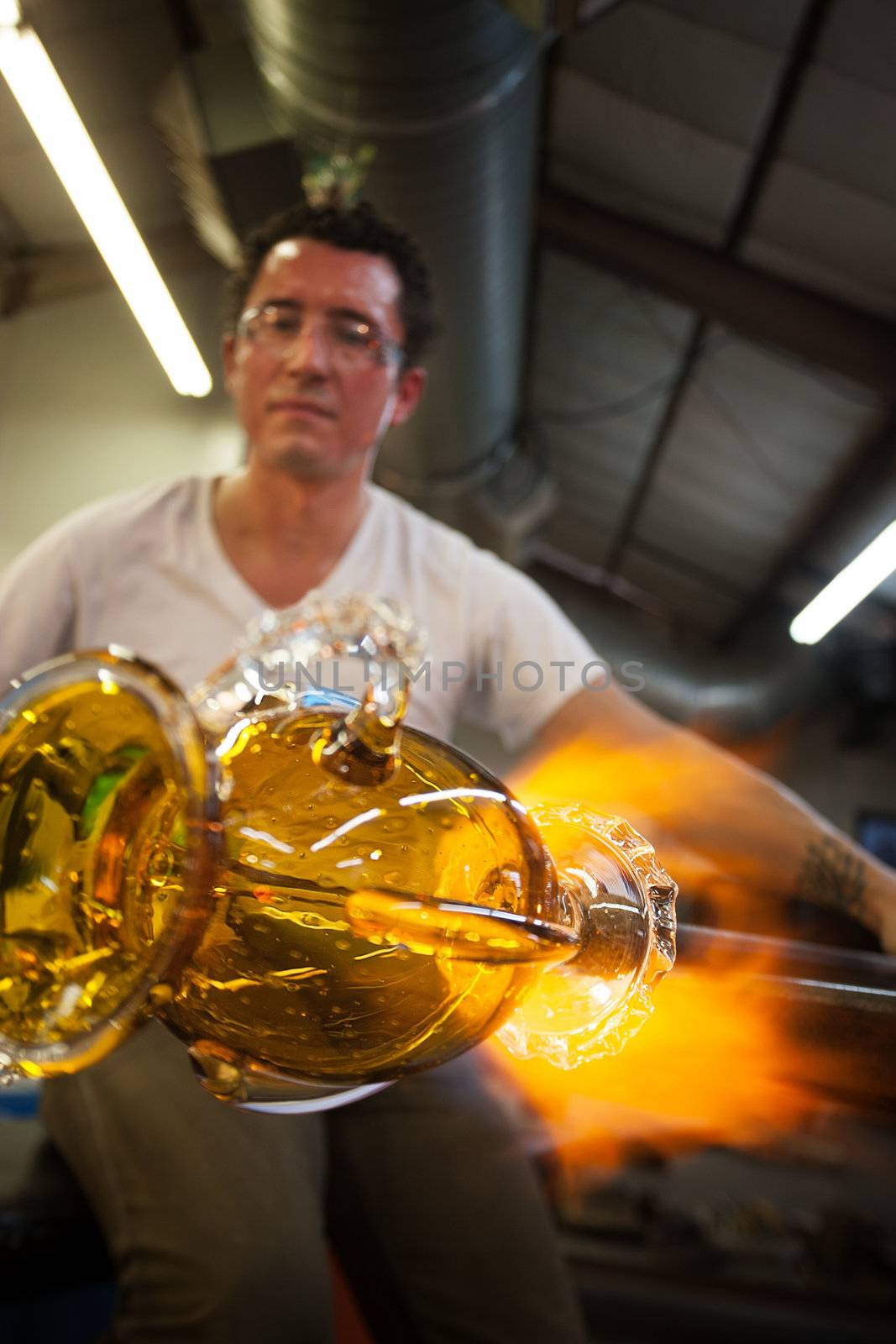 Latino glass artist sculpting glass vase with blowtorch
