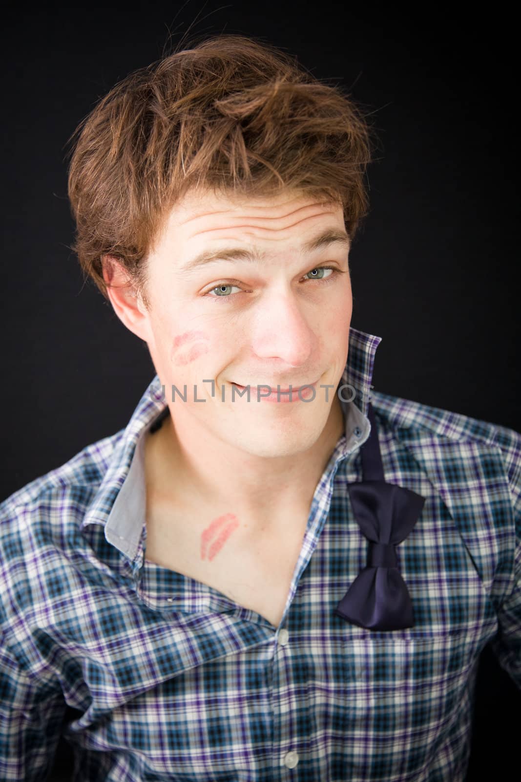 A young man that had some fun and got a kiss trace on the cheek