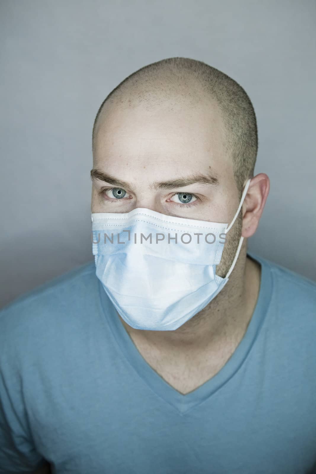 Young doctor with bald head wearing a mask and on a gray background (in studio)