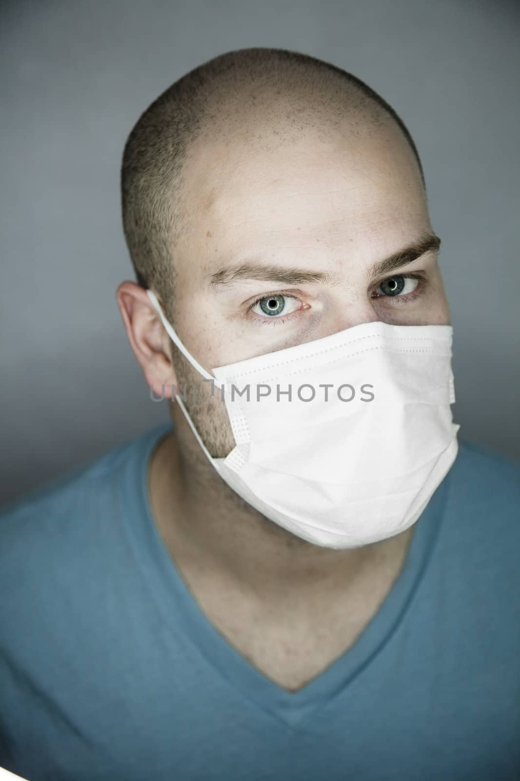 Young doctor with bald head wearing a mask and on a gray background (in studio)