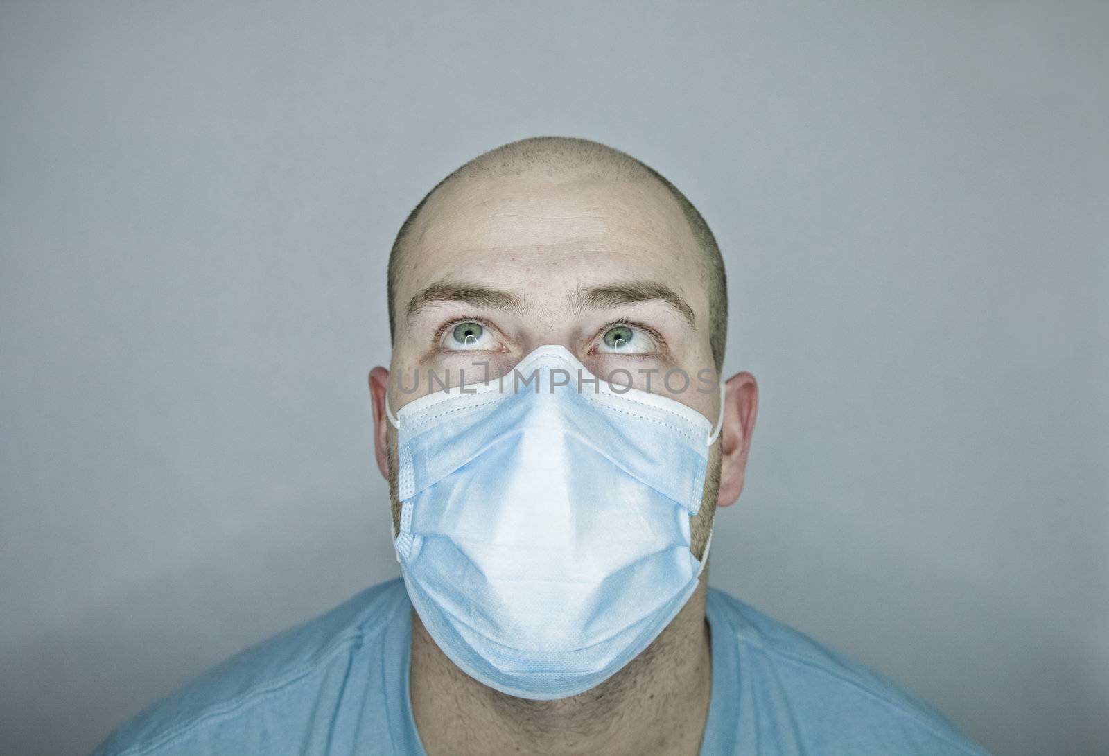 Young doctor with bald head wearing a mask and on a gray background (in studio)