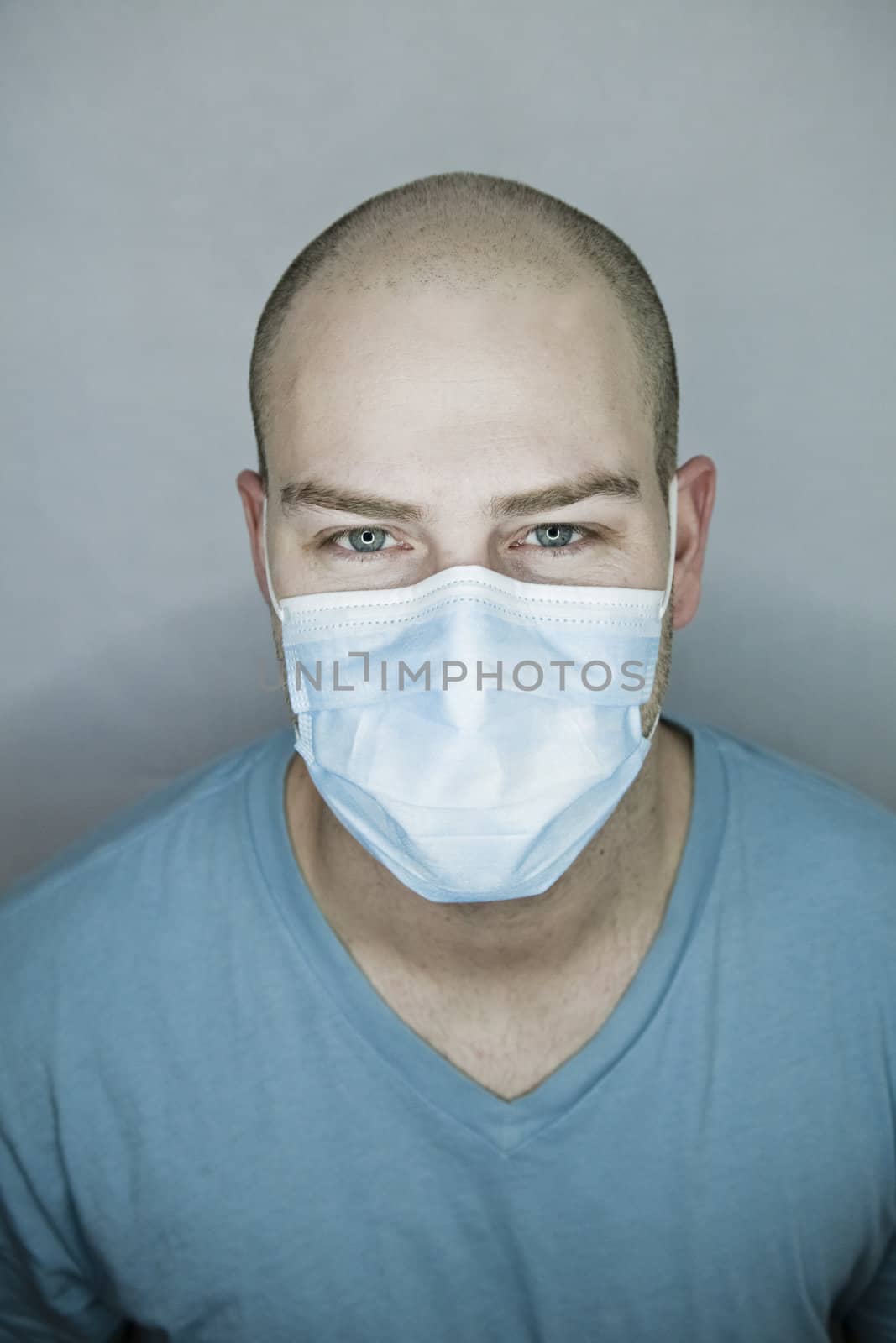 Young doctor with bald head wearing a mask and on a gray background (in studio)