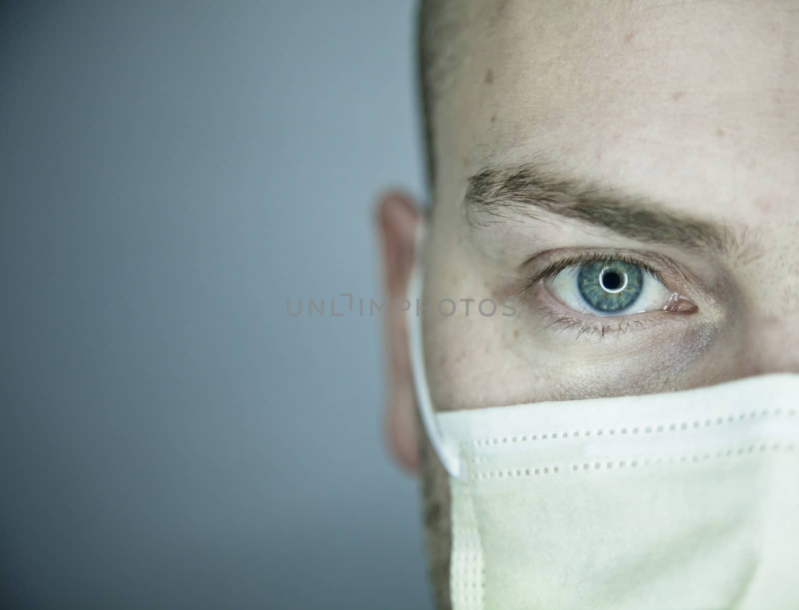 Young doctor with bald head wearing a mask and on a gray background (in studio)