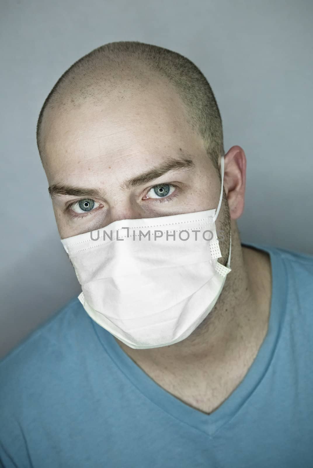 Young doctor with bald head wearing a mask and on a gray background (in studio)
