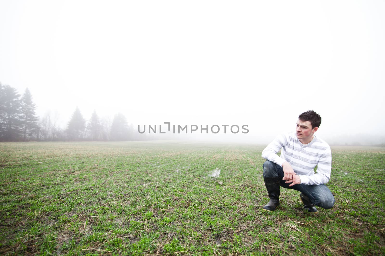 Young adult in a foggy and wet field