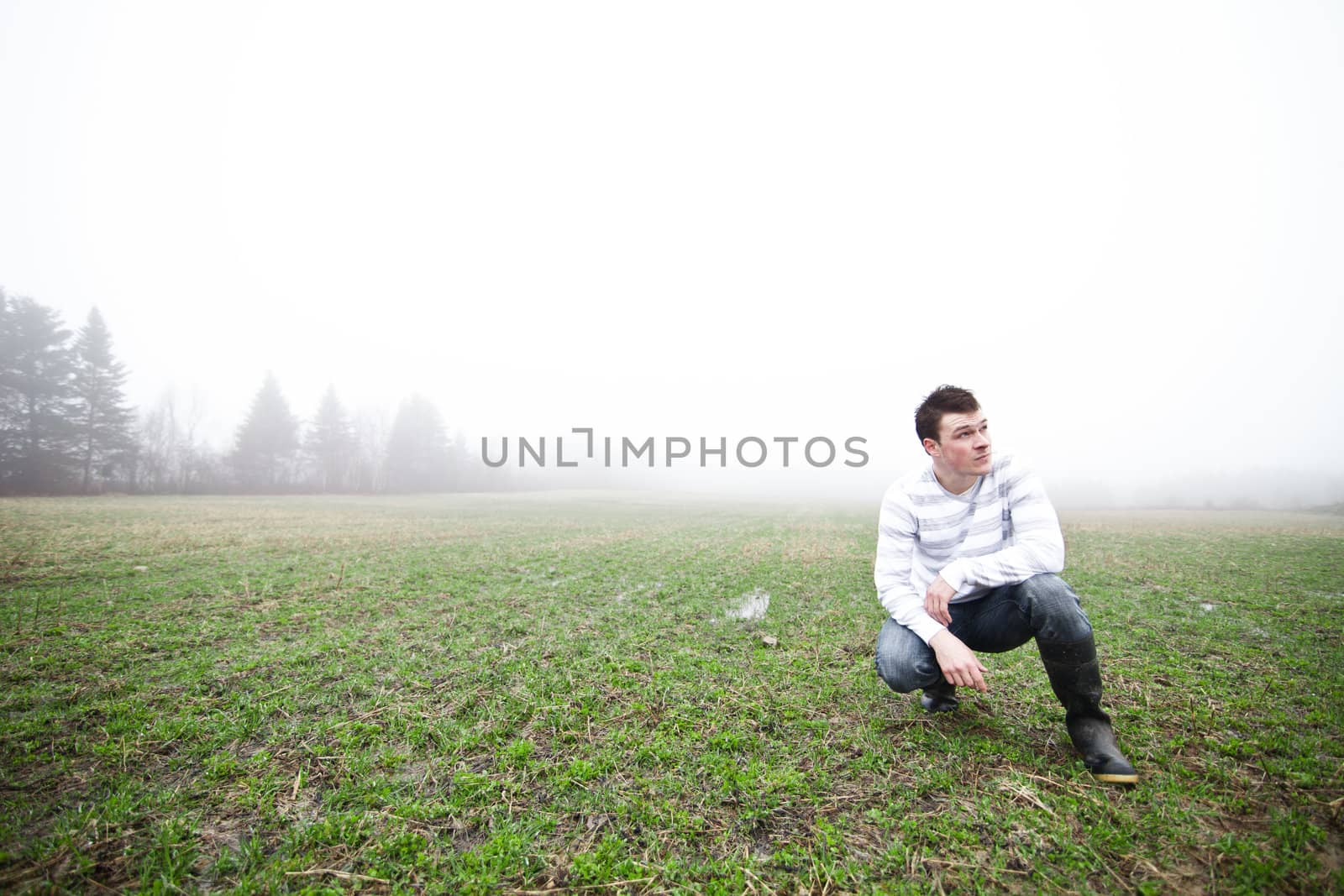 Young adult in a foggy and wet field