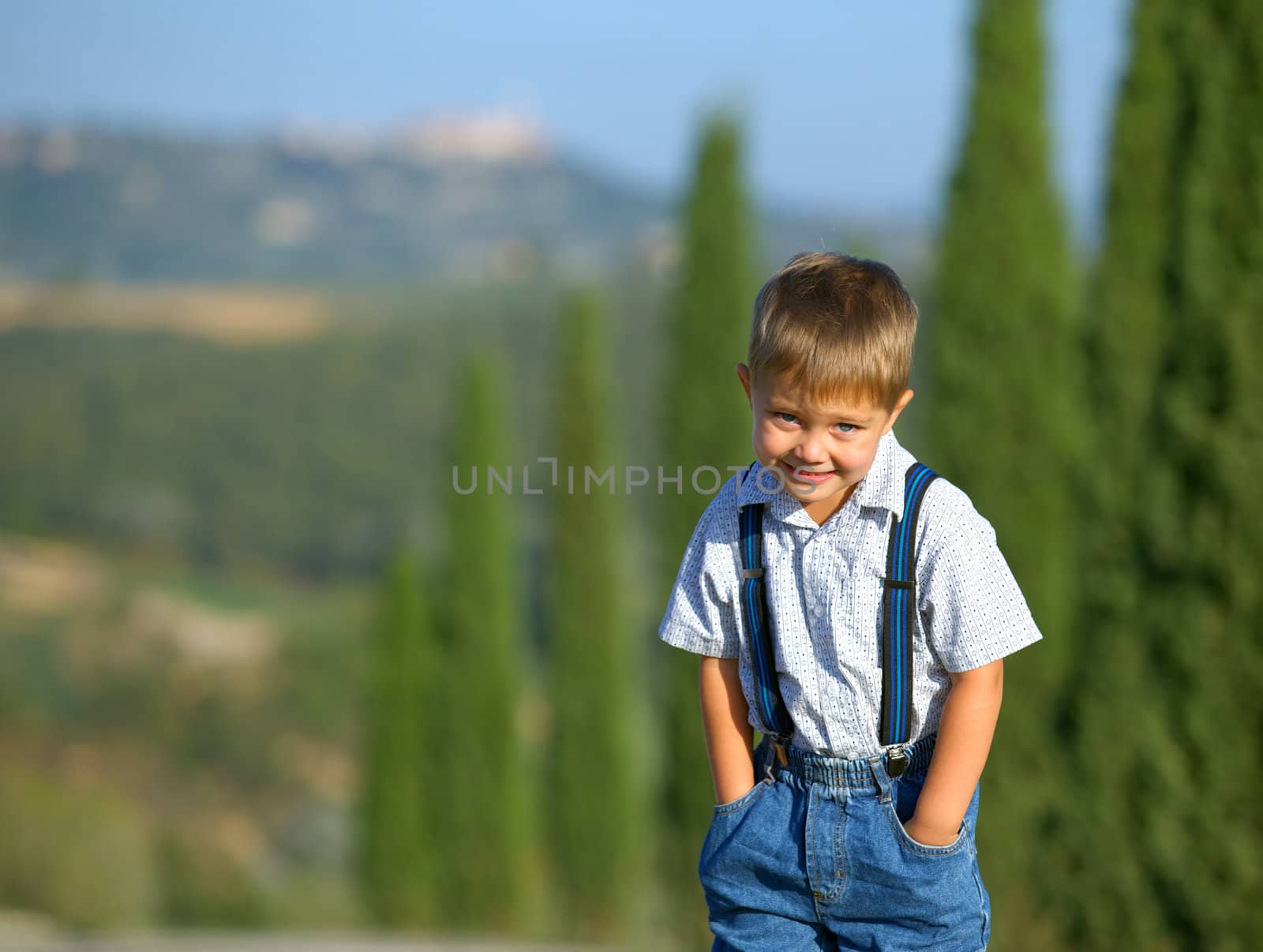 Cute boy having fun on vacations in Tuscan against cypress alley background