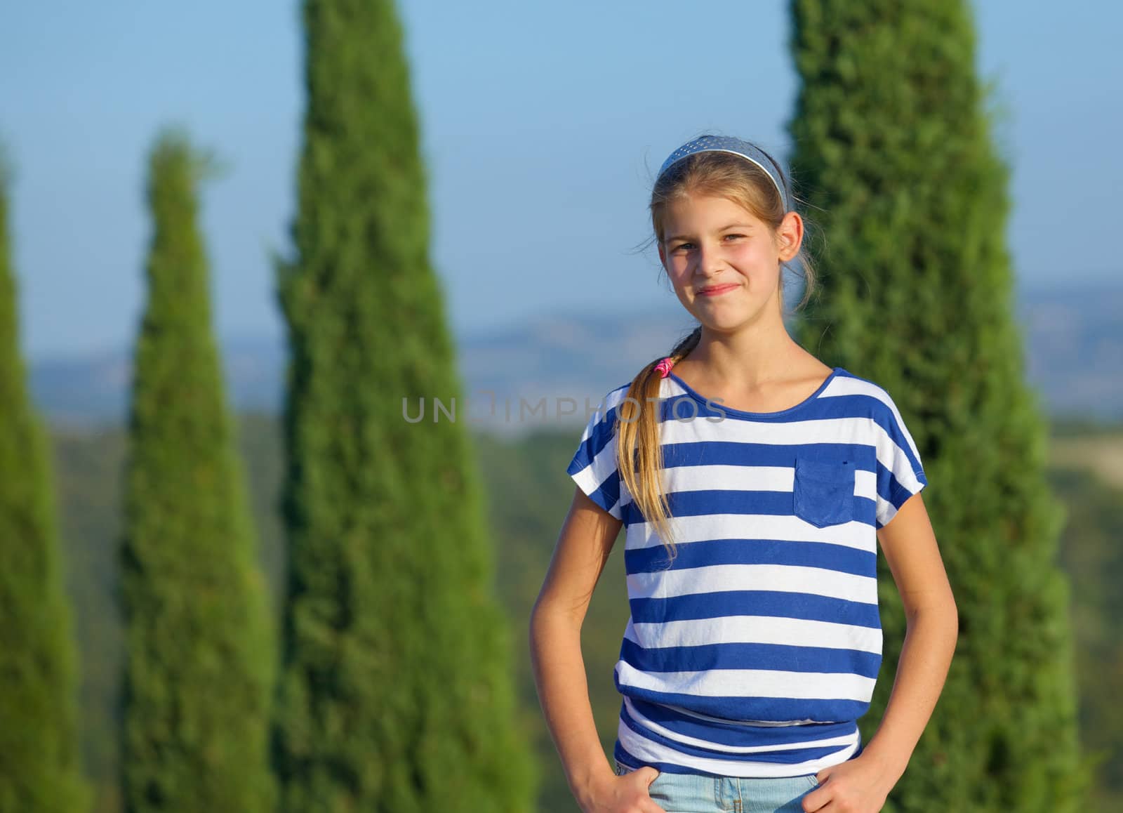 Happy girl having fun on vacations in Tuscan against cypress alley background