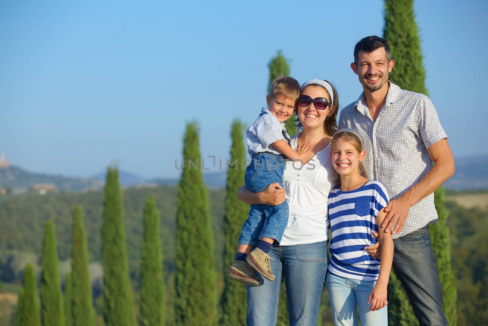 Happy family having fun on vacations in Tuscan against cypress alley background