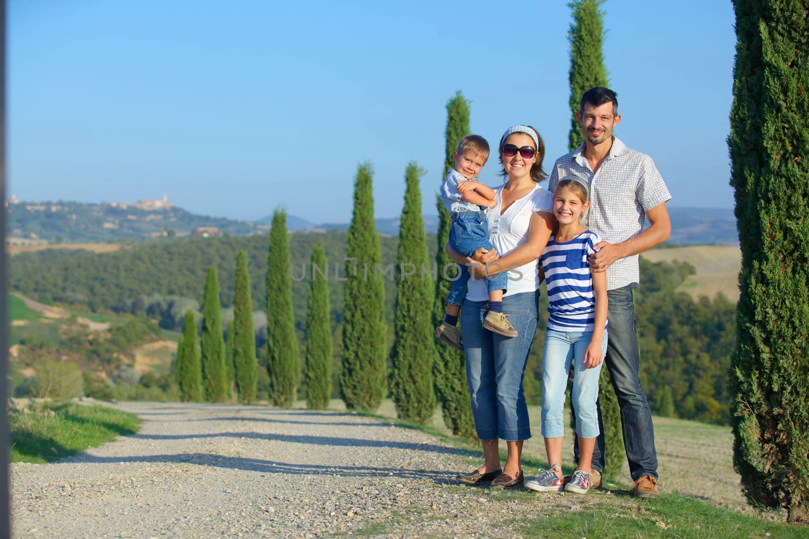 Happy family having fun on vacations in Tuscan against cypress alley background