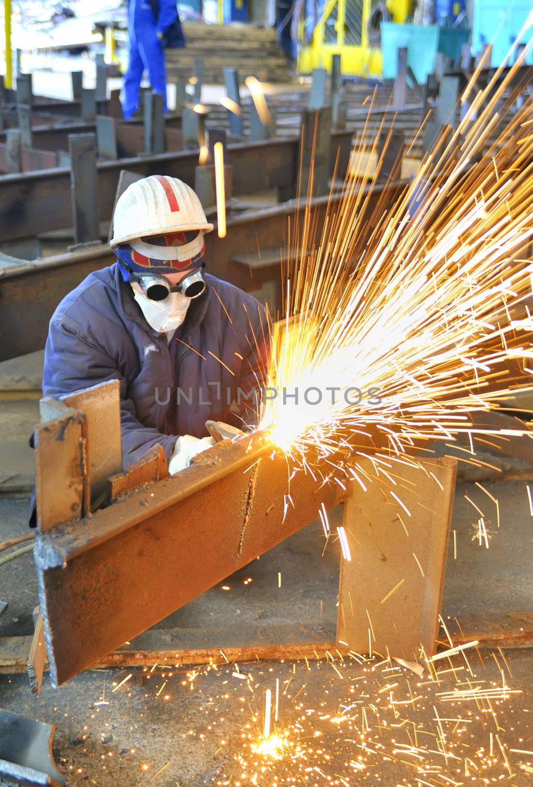 worker using torch cutter to cut through metal in factory