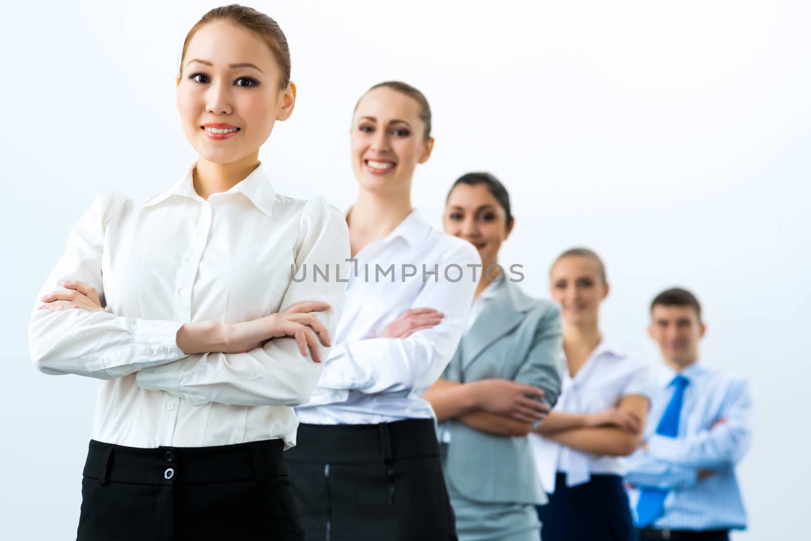 group of business people standing in a row, smiling and crossing his arms