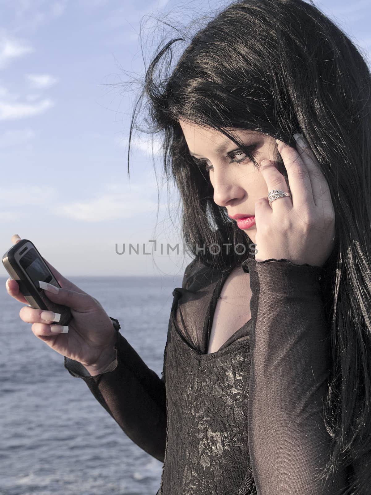 Young woman lookin the display of her phone at seaside