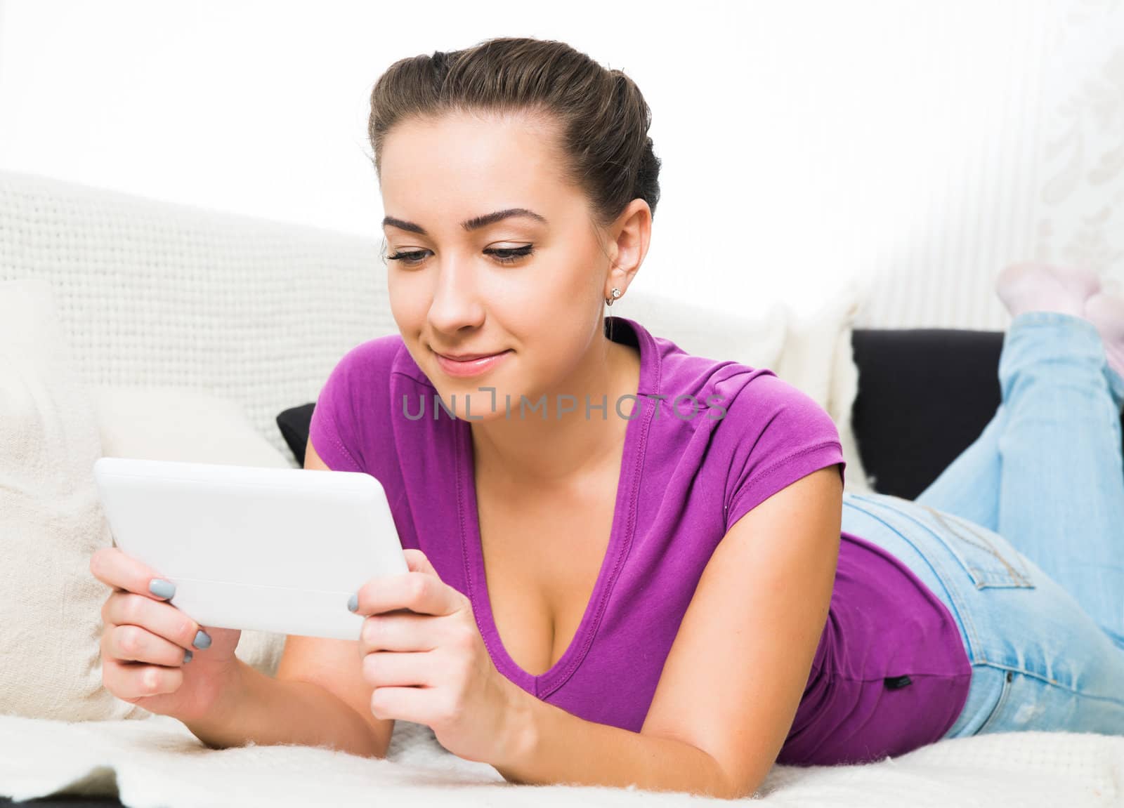 Young Brunette girl with tablet pc on the sofa.