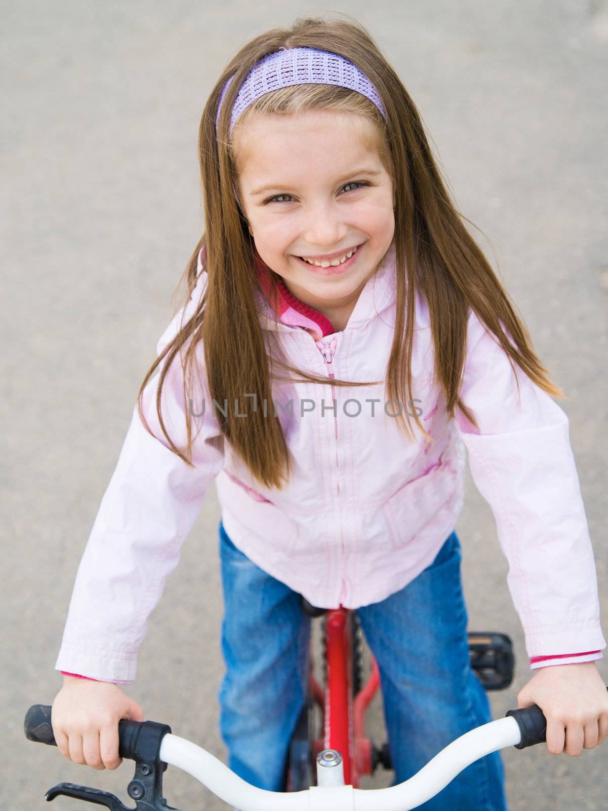 Portrait of a little girl on a bicycle in summer park outdoors