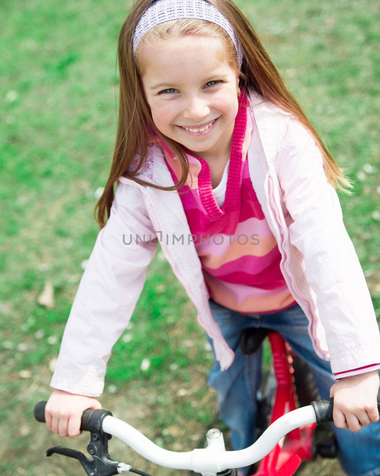 Portrait of Cute smiling little girl with bicycle in summer park outdoors