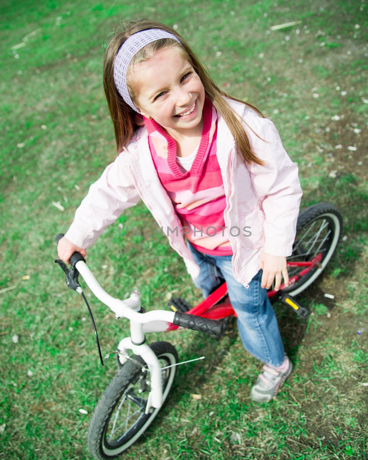 Cute smiling little girl with bicycle in summer park outdoors