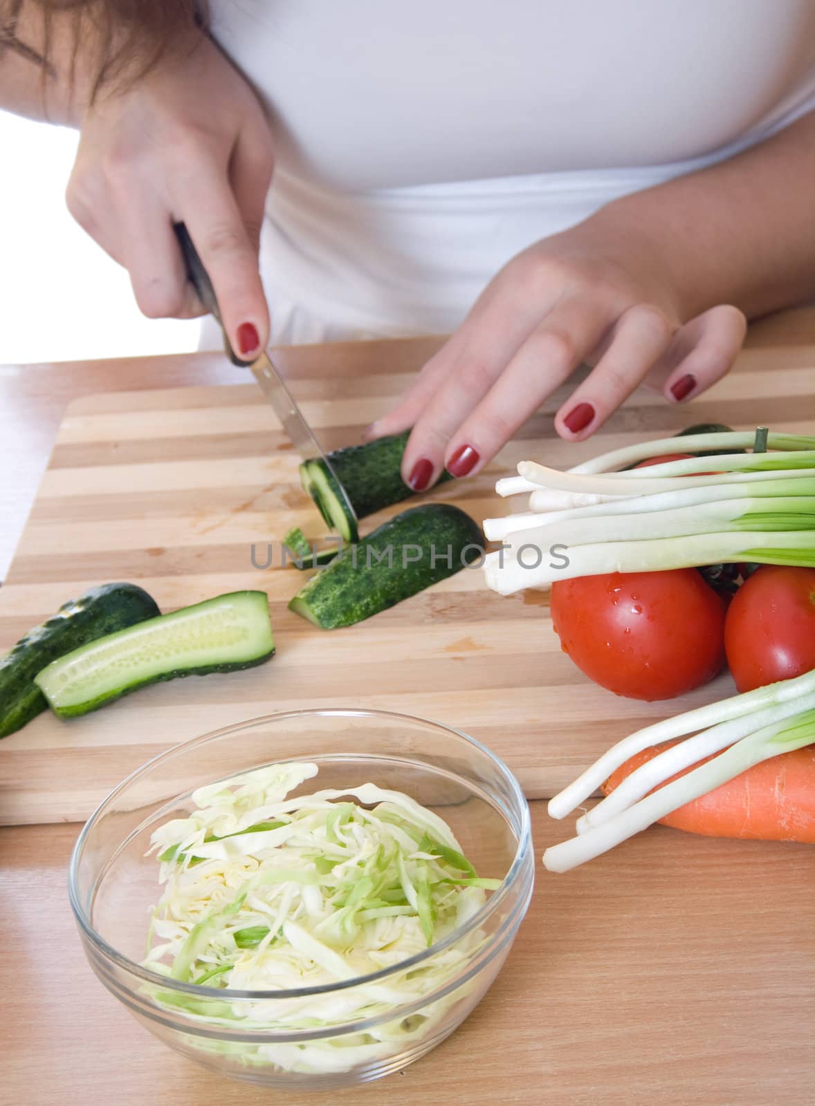 Women's hands cut cucumber salad