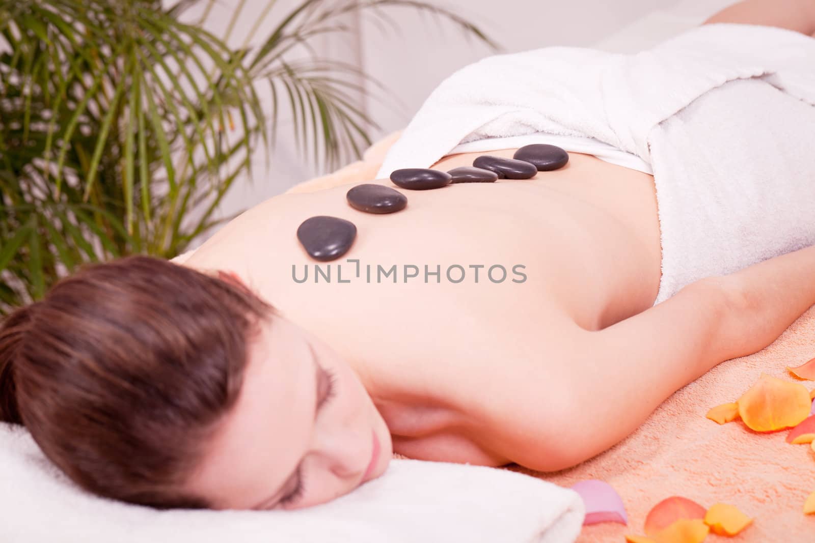 young attractive woman get hot stone massage by professional in wellness spa salon