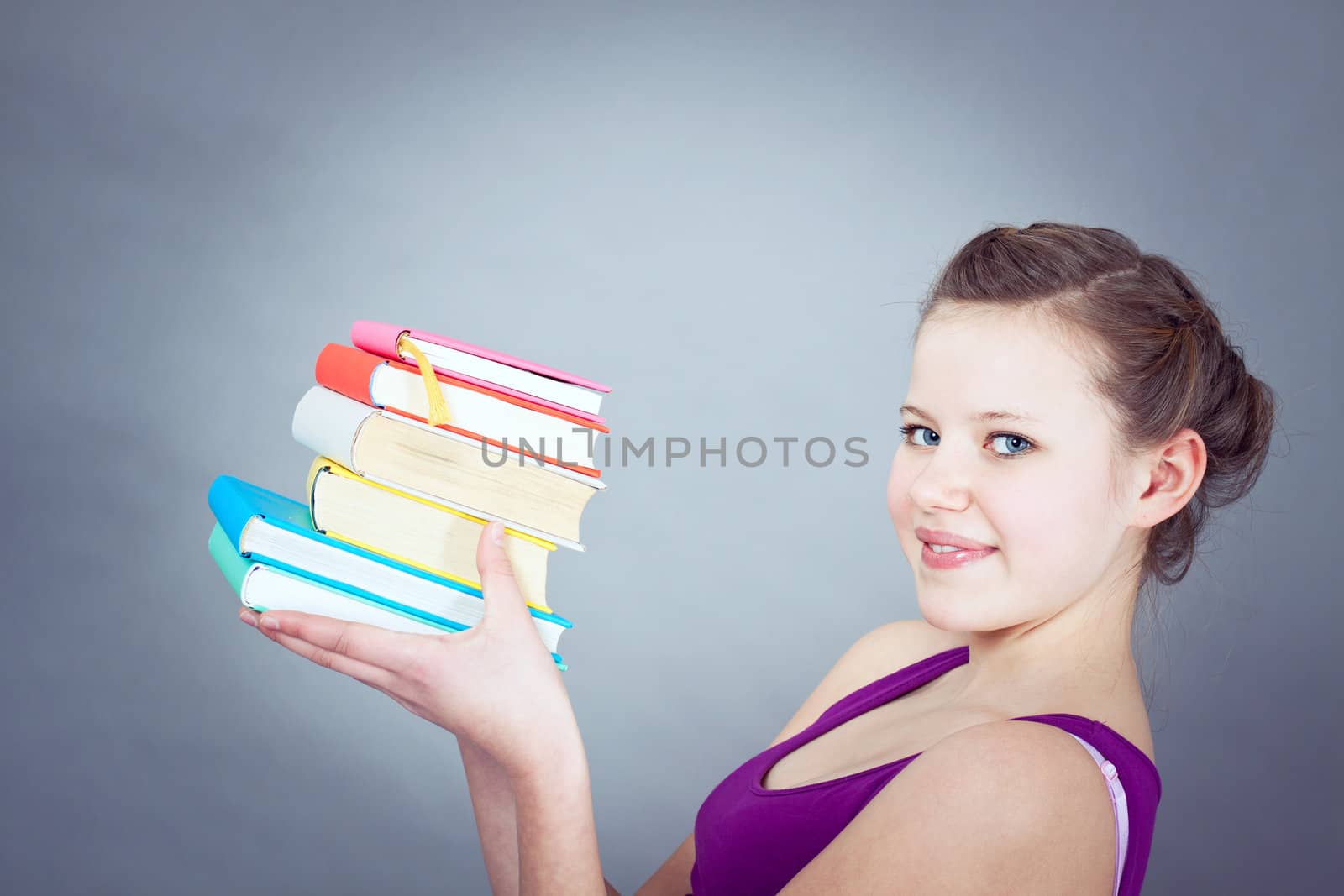 Silly smiling schoolgirl with glasses and lots of books having fun