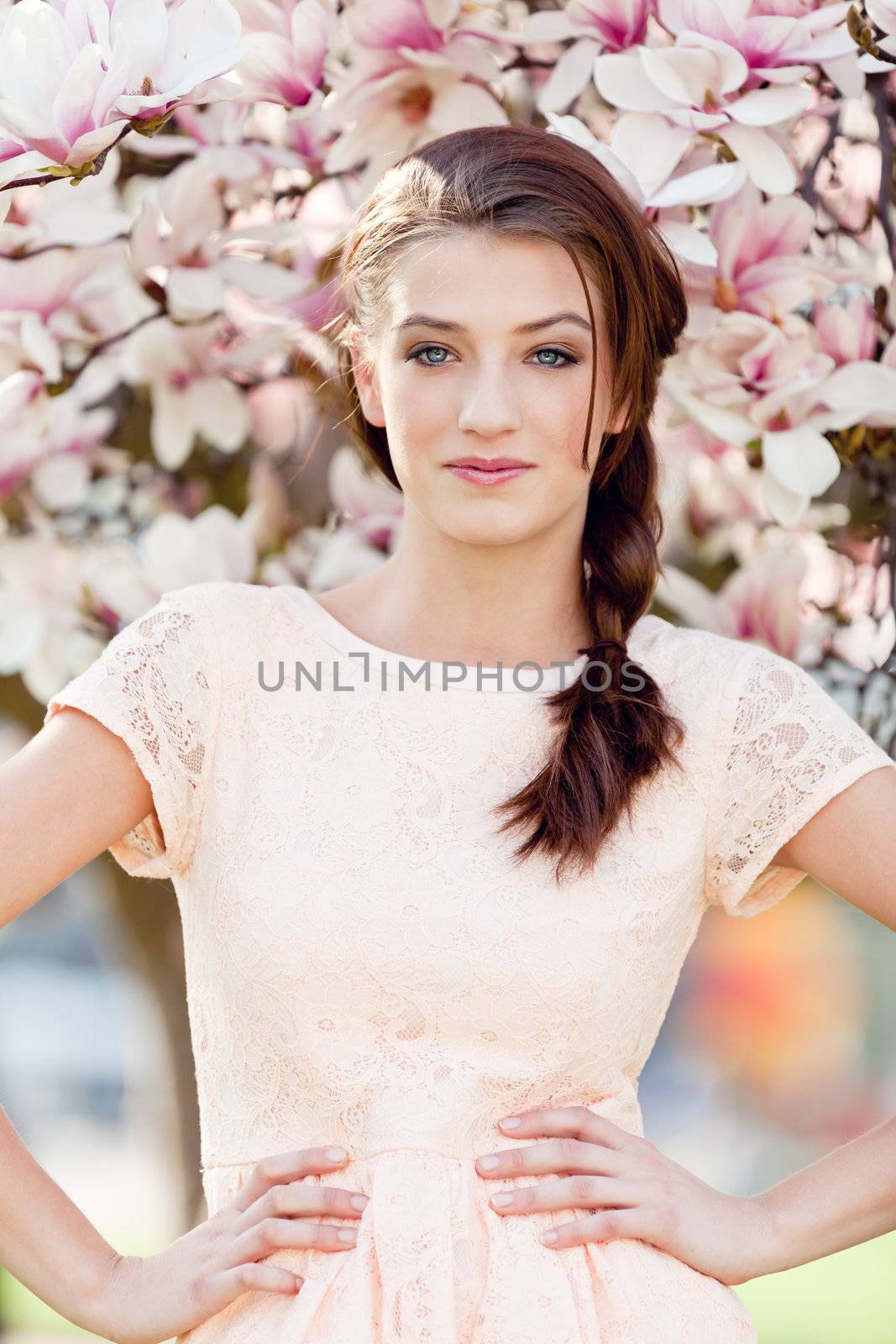 beautiful smiling woman and pink magnolia outside in spring