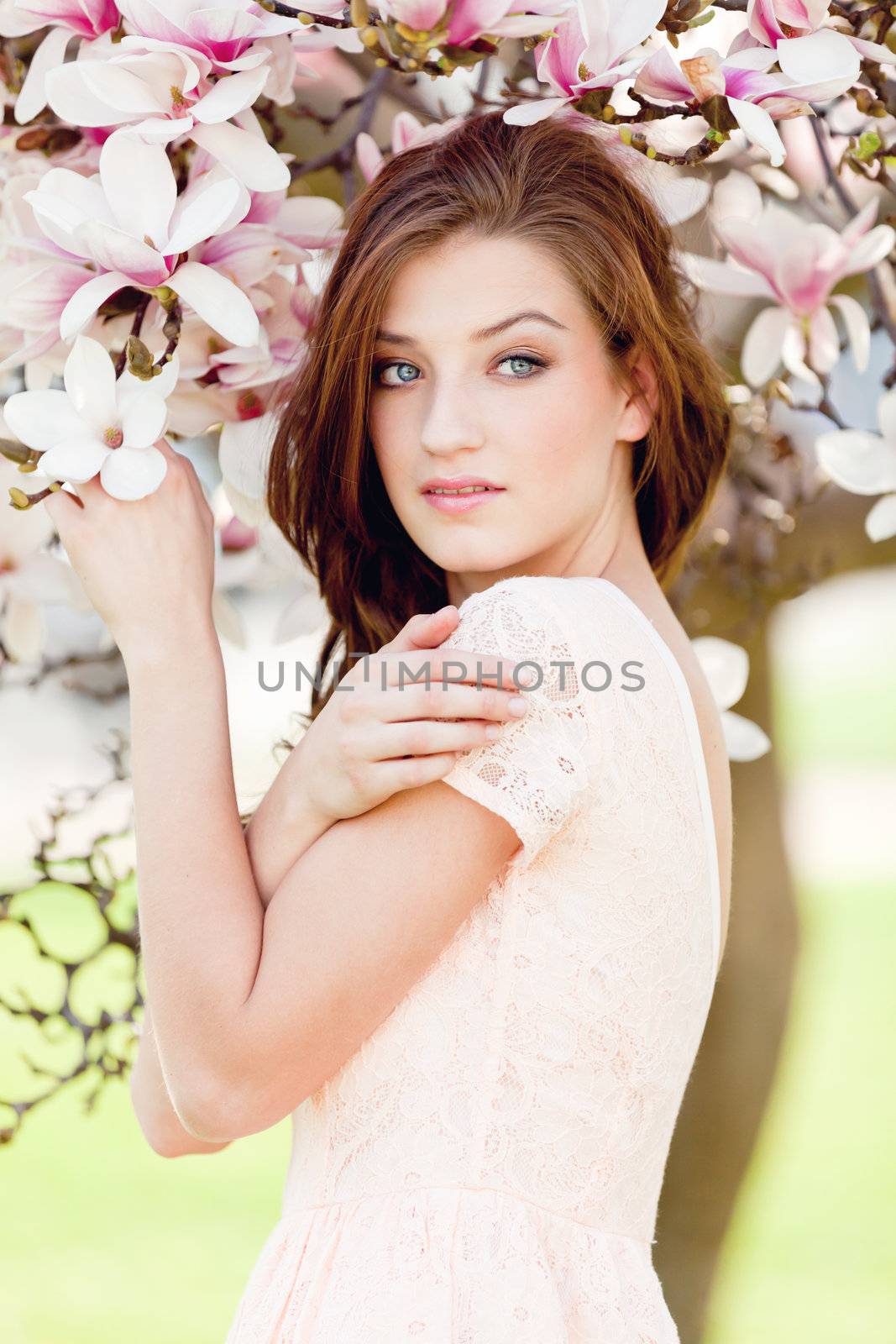 beautiful smiling woman and pink magnolia outside in spring