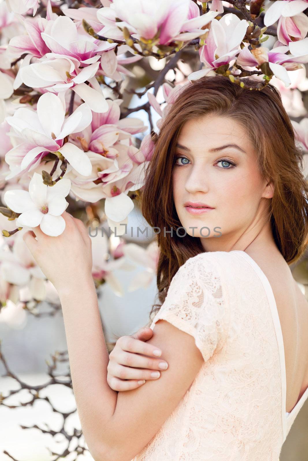 beautiful smiling woman and pink magnolia outside in spring