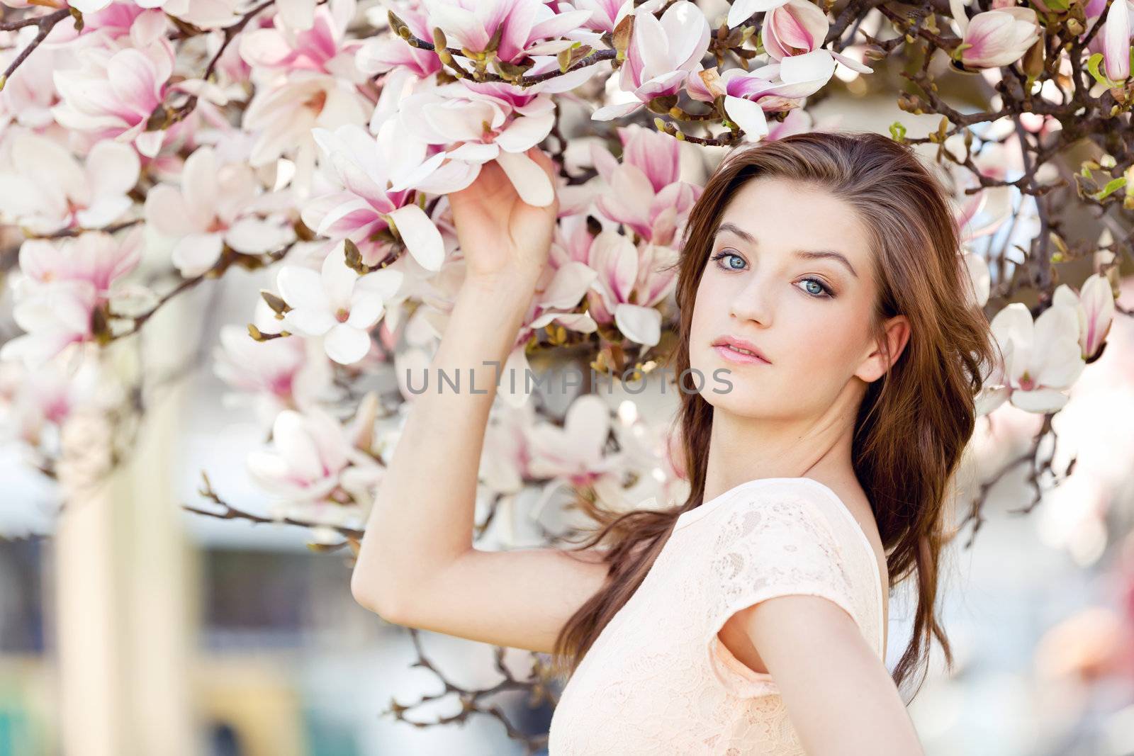 beautiful smiling woman and pink magnolia outside in spring