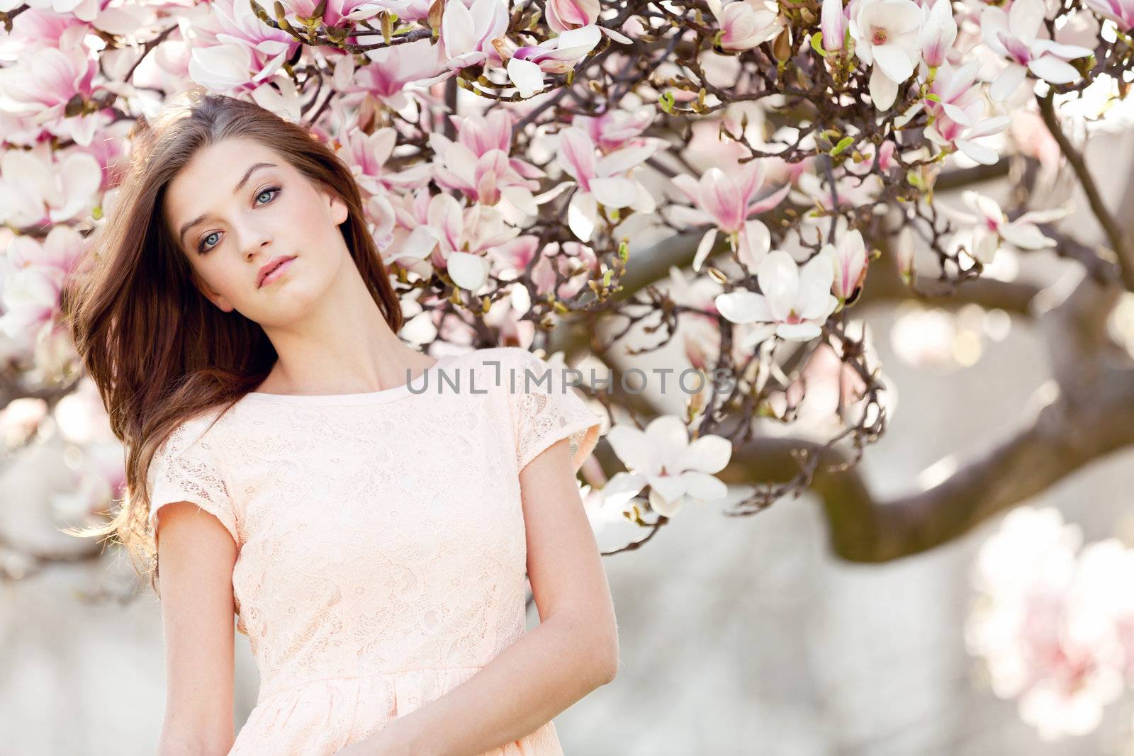 beautiful smiling woman and pink magnolia outside in spring